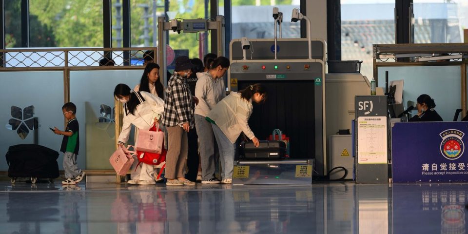 Passageiros passam por uma área de controle de segurança em um terminal aeroportuário.