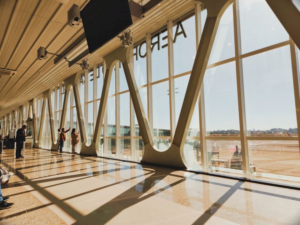 Interior iluminado de um terminal aeroportuário brasileiro, com estrutura moderna e área de circulação de passageiros.