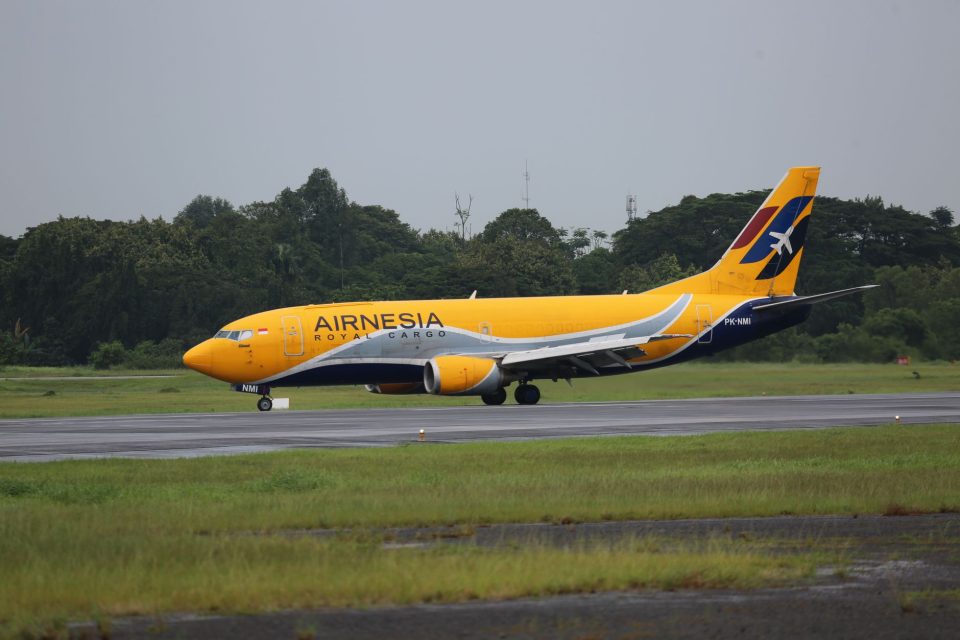 Avião cargueiro taxiando na pista de um aeroporto, com vegetação ao fundo