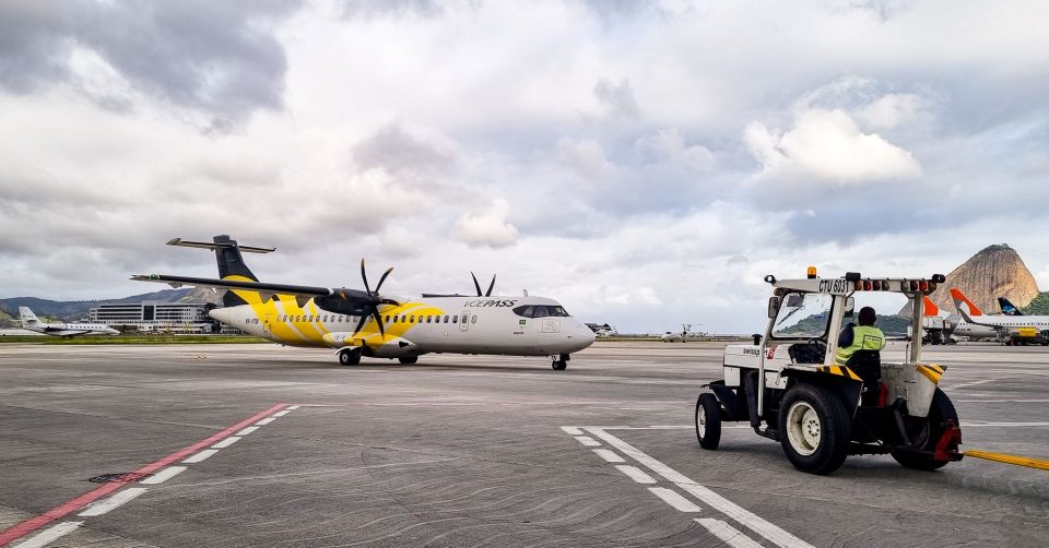 Avião turboélice na pista de um aeroporto do Rio de Janeiro, acompanhado por equipe de solo.